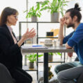 Practitioner having a difficult conversation with a young man at a table