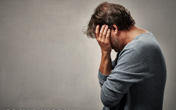 Man covering his face to depict sadness