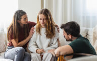 A couple comforting their daughter at home