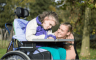 Disabled girl in a wheelchair relaxing outside with a care assistant