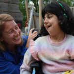 A support worker working with a young girl in a wheelchair