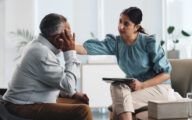 A social worker comforting an older man while carrying out a needs assessment