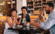 Young friends having a great time in restaurant. Multiracial group of young people sitting in a coffee shop and smiling.