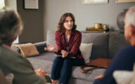 Professional sitting on a sofa talking to an older couple